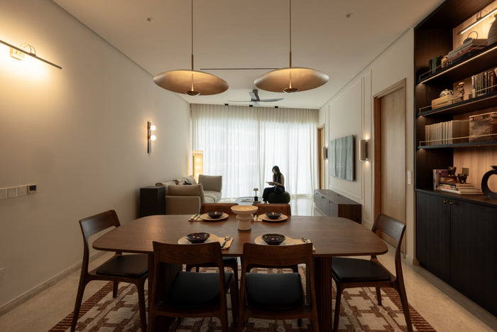 Open-plan living and dining room of a completed home, with someone reading by the window