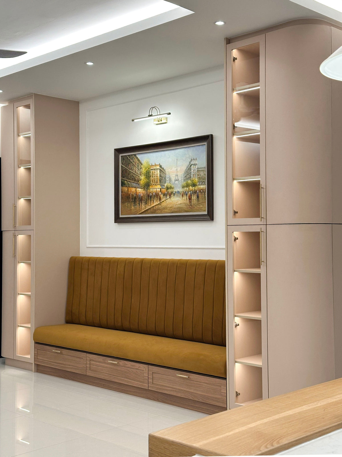 A dining banquette with ochre velvet between lit display cabinets, in a home Sundays in Bed designed at Setia Sky Seputeh, Seputeh