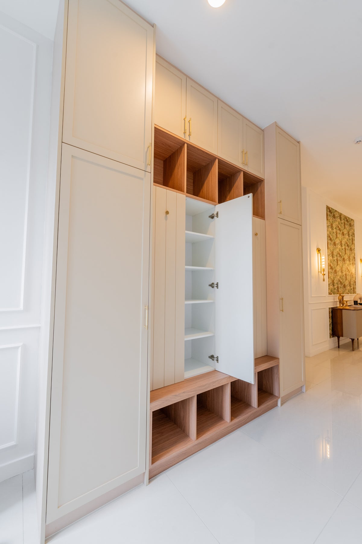 An entrance wall with full-height cream cabinets for shoes, luggage and coats, in a home Sundays in Bed designed at Setia Sky Seputeh, Seputeh