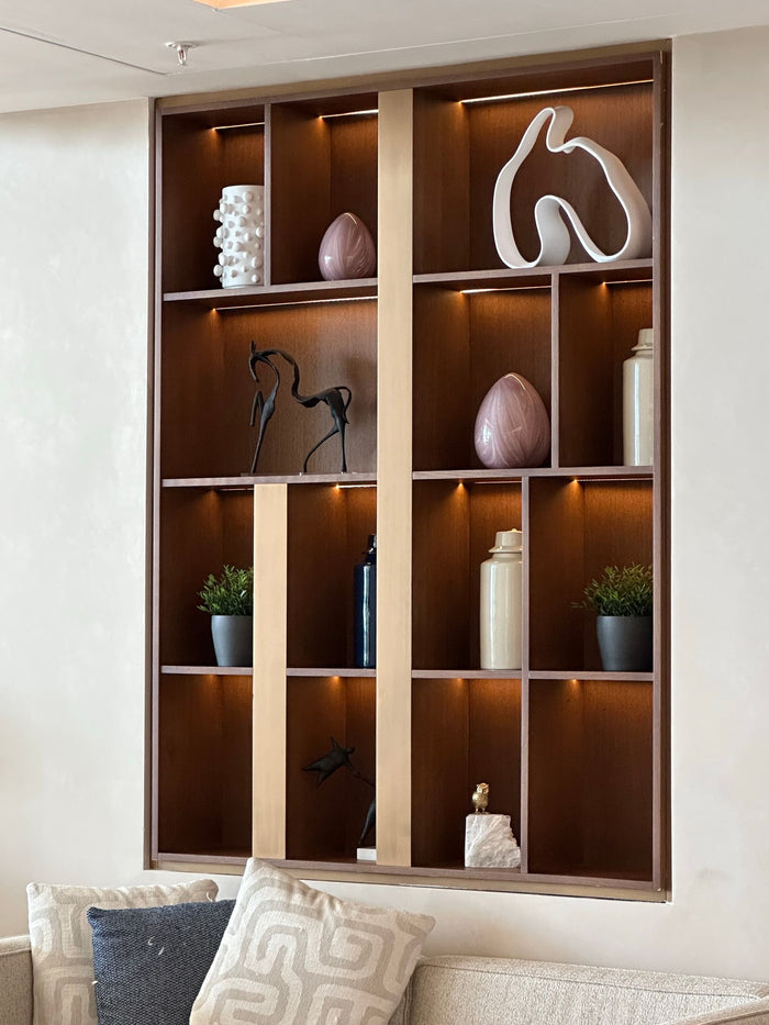Backlit display shelving styled with ceramics, sculptural objects and greenery