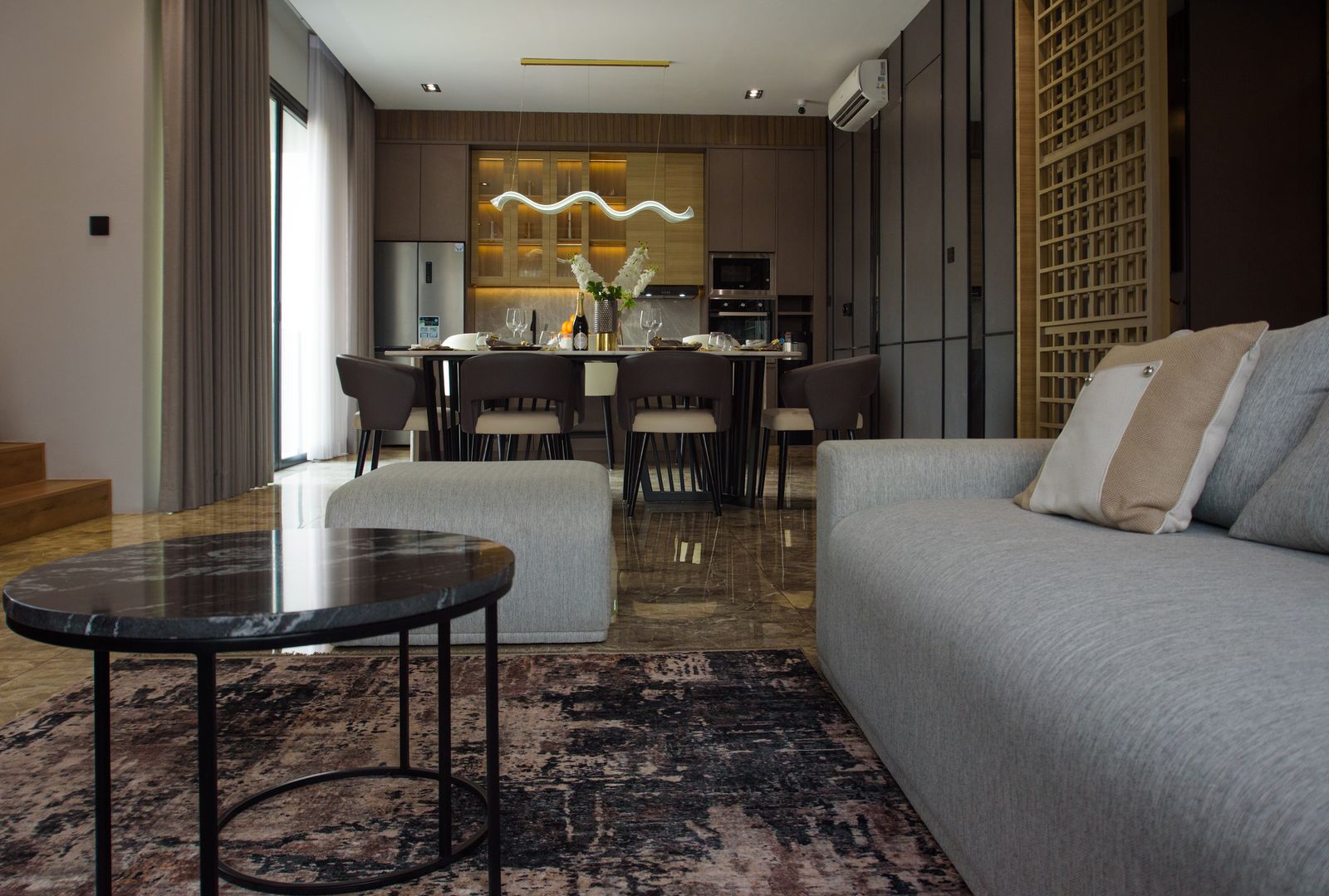 Contemporary open-plan condo living and dining space with marble floors and warm wood cabinetry