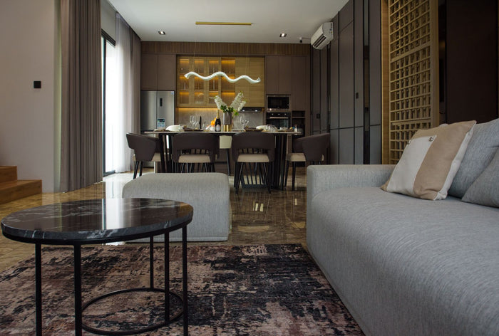 Contemporary open-plan condo living and dining space with marble floors and warm wood cabinetry