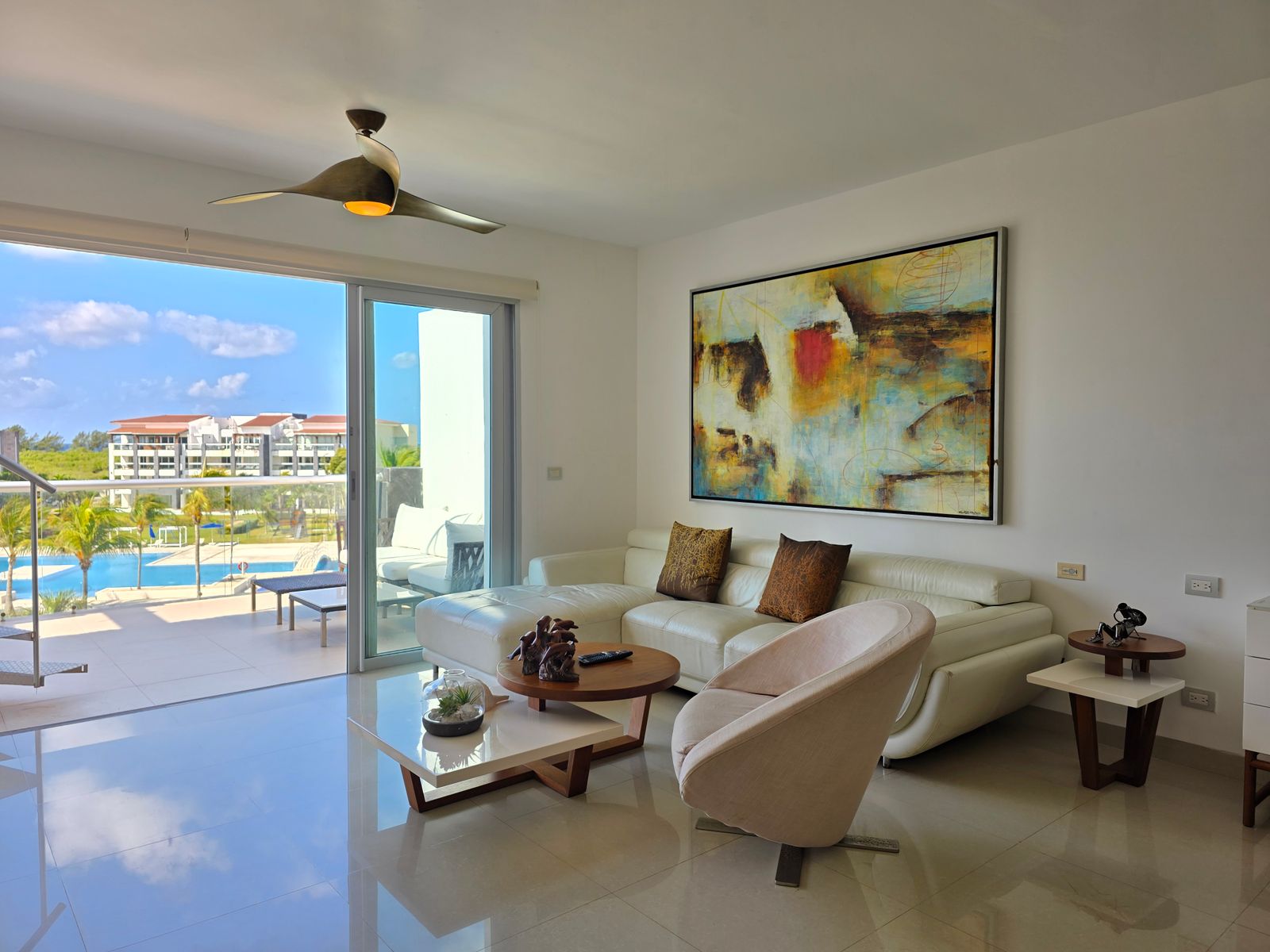 Bright condo living room with a balcony view over a pool and quality furnishings