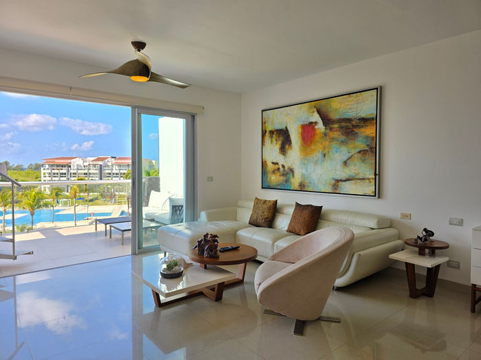 Bright condo living room with a balcony view over a pool and quality furnishings