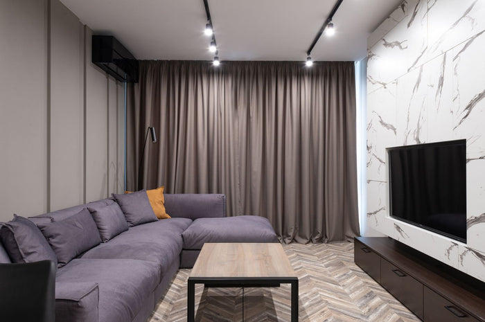 Modern condo living room with a sculptural sofa, marble feature wall and track lighting