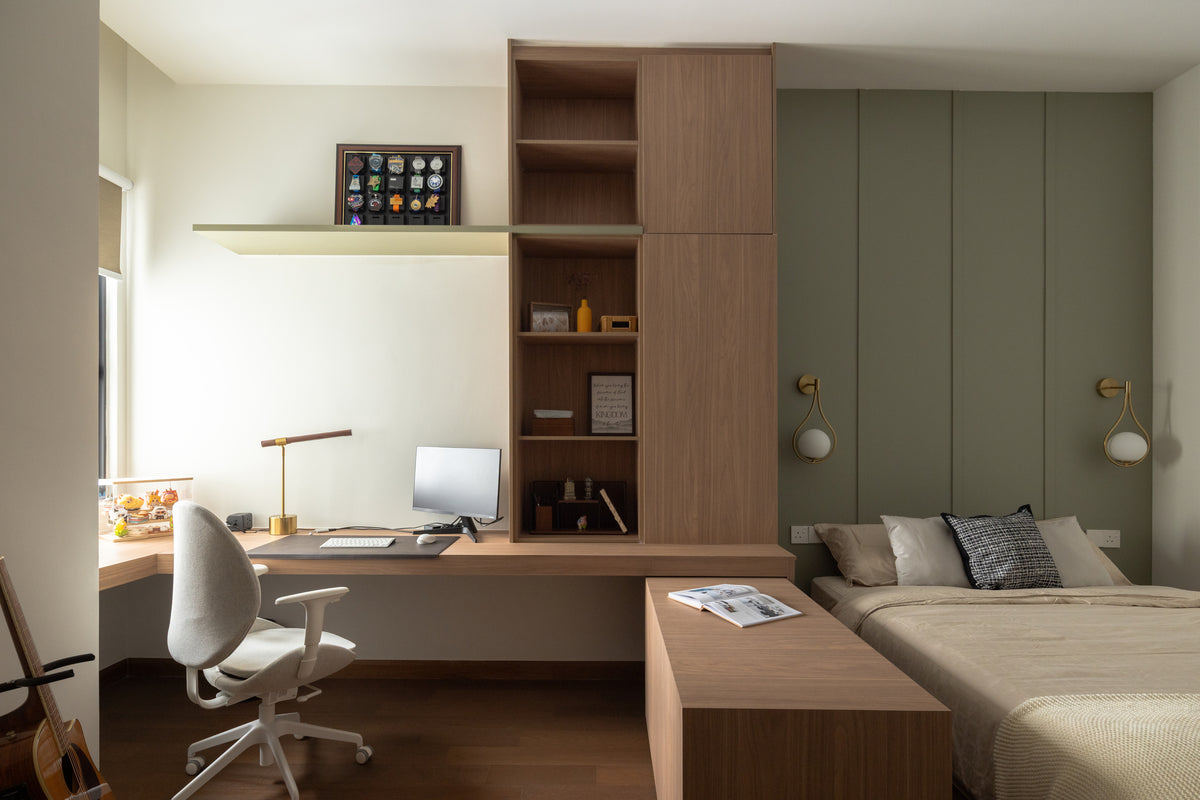 A bedroom with a built-in desk and shelving, a sage panelled wall and wall lights, in a home Sundays in Bed designed at Bangsar Hill Park, Bangsar