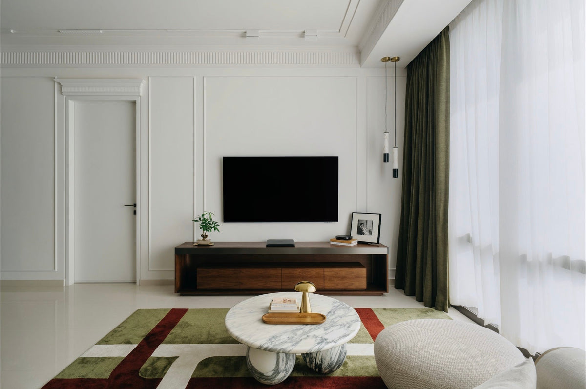 Living room in Justin's three-bedroom condo, with a walnut media console, a round marble coffee table and a patterned rug
